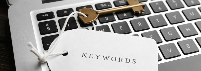 A bronze key marked "Keywords" lies on laptop keyboard.