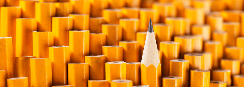 A bunch of yellow pencils, all tip down, where a single yellow pencil faces with the tip up, thus emerging from the masses.