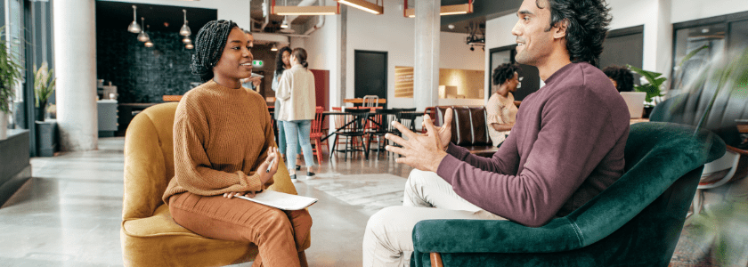 A man and a woman sitting in a café discussing a project.